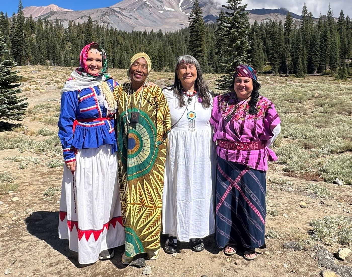 Four grandmothers in traditional dress standing together at Mt. Shasta